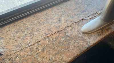 This BEFORE image shows the damaged granite behind the faucet. Photo