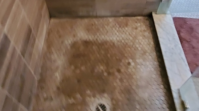 This BEFORE image shows the shower floor with soap scum buildup. Photo