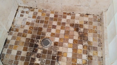 As you can see, the travertine shower pan was in very poor condition. Photo