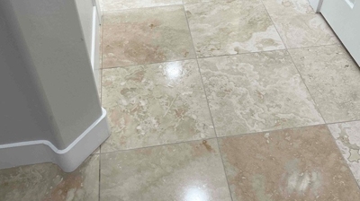 The overhead lights reflect on the polished travertine kitchen floor in this AFTER image. Photo