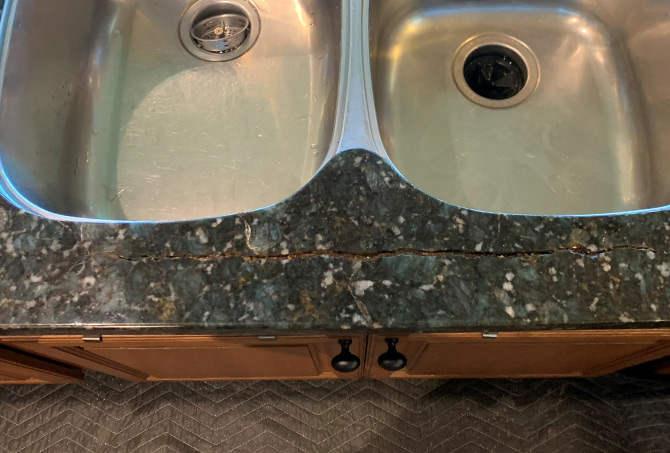 This granite countertop is cracked. The crack runs along the front edge of the kitchen sink.