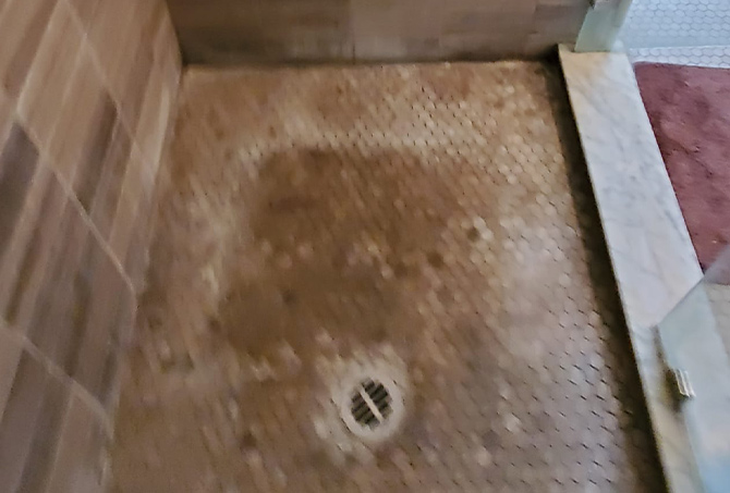 This BEFORE image shows the shower floor with soap scum buildup.
