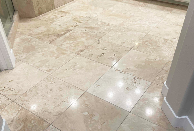 The overhead lights reflect on the surface of the polished travertine.