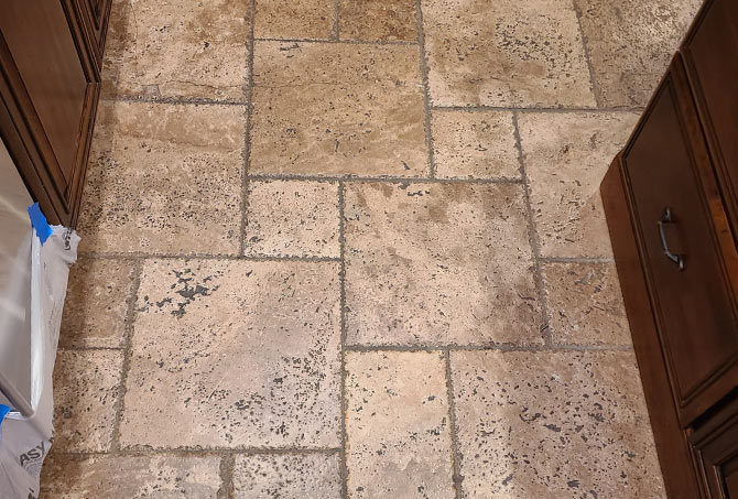 This travertine floor has a dark and dirty appearance.